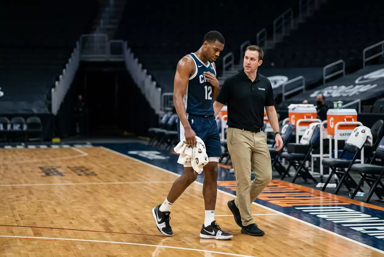 Basketball player walking off a hardwood NBA court with a towel after an early injury